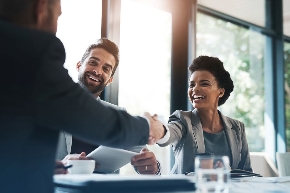 Women shaking a hand of a man at a meeting